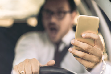 Close up of a terrified businessman using cell phone during his drive while about to crash
