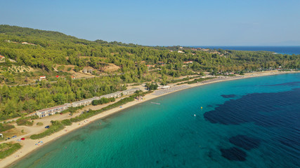 Fototapeta na wymiar Aerial drone view of iconic sandy turquoise organised with sun beds and umbrellas beach of Paliouri in Kassandra Peninsula, Halkidiki, North Greece