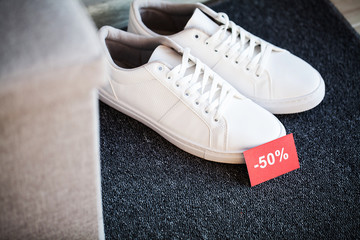 Pair of new stylish white sneakers with discount on gray background.