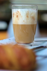 Close-up detail of a Cafe latte and a croissant on a coffee shop table