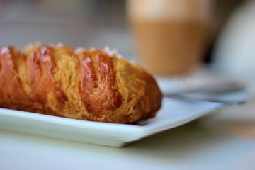 Close-up detail of a Cafe latte and a croissant on a coffee shop table