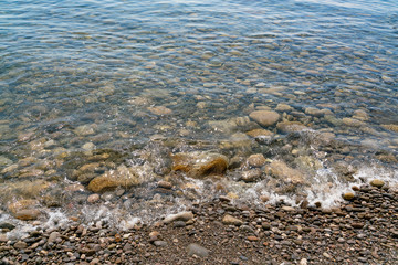 Transparent water splashing on the stones on the shore