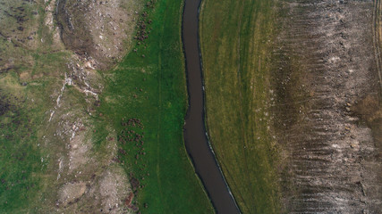 A river located in the middle of a meadow shot perpendicularly from above - obrazy, fototapety, plakaty