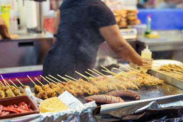 Man cooking juicy spiced marinated meat kebab on skewers