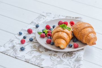 croissants with raspberries and blueberries with coffee