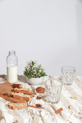 Coffee with milk, cookies, cinnamon and fruits on the tablecloth.