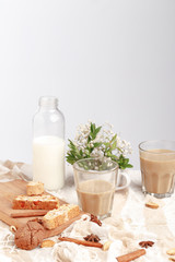Coffee with milk, cookies, cinnamon and fruits on the tablecloth.