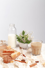 Coffee with milk, cookies, cinnamon and fruits on the tablecloth.