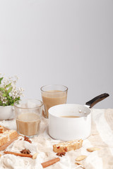 Coffee with milk, cookies, cinnamon and fruits on the tablecloth.