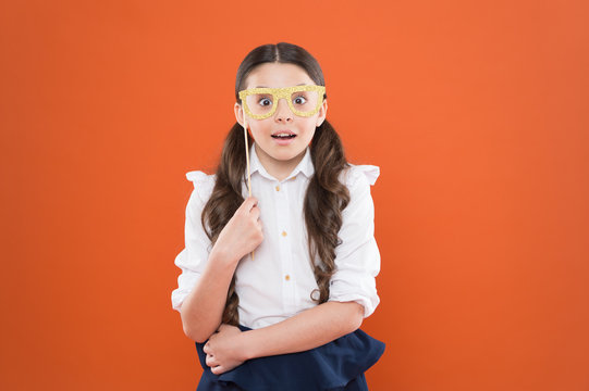 School Party Concept. What Does It Mean Being Smart. Little Smart Schoolgirl On Orange Background. Child Smart Look Through Photo Booth Props Eyeglasses. Small Kid Wearing Eye Glasses In Smart Style