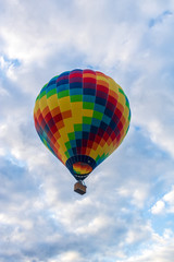Colorful hot air balloon soaring against a mostly cloudy sky