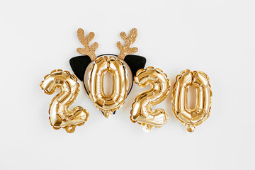 Foil balloons in the form of numbers 2020 and toy antlers of a deer . New year celebration. Gold and silver Air Balloons. Holiday party decoration.