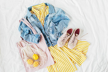 Blue jean jacket and Yellow dress  with eco bag and sneakers on white bed. Women's stylish autumn...
