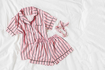 Pajamas sleeping kit. Classic pink sleep dress with stripes in bed. Good morning concept. Flat lay,...