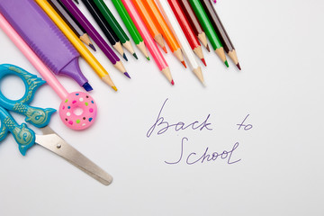 colored pencils, scissors, pen, marker on a white piece of paper copy space top view back to school