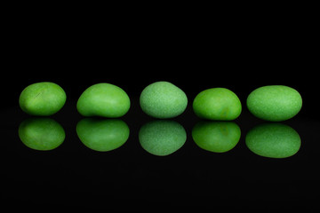 Group of five whole green sugared nut dragee isolated on black glass
