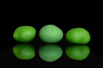 Group of three whole green sugared nut dragee isolated on black glass