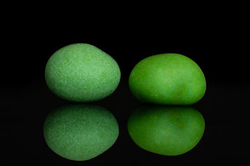Group of two whole green sugared nut dragee isolated on black glass