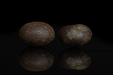 Group of two whole brown sugared nut dragee isolated on black glass