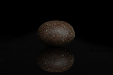 One whole brown sugared nut dragee isolated on black glass
