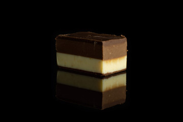 One whole mellow two coloured nougat piece isolated on black glass