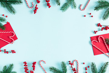 Christmas modern composition. Fir tree branches, red berries, envelopes, Xmas decorations on pastel blue background. Christmas, New Year, winter concept. Flat lay, top view, copy space