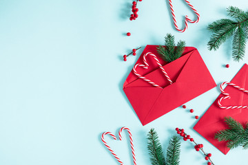 Christmas modern composition. Fir tree branches, red berries, envelopes, Xmas decorations on pastel blue background. Christmas, New Year, winter concept. Flat lay, top view, copy space