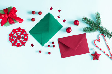 Christmas modern composition. Gift, fir tree branches, red berries, envelopes, Xmas decorations on pastel blue background. Christmas, New Year, winter concept. Flat lay, top view, copy space