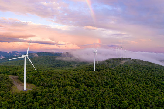 Wind Turbines on Mountain Ridge at Sunset with Rainbow