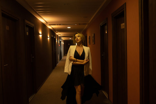 Luxury girl in black dress at night in the hotel corridor.