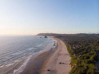 embankment of the ocean with sand and a road in the forest, at sunset shot from a high point, frame from a height