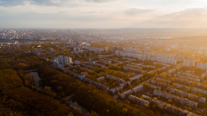 Obraz premium Shot of a beautiful city located at the edge of a forest, and a sky, during sunrise.