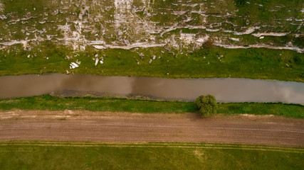 Aerial view of an abrupt valley leading towards a river next to a road on the edge of a plain.