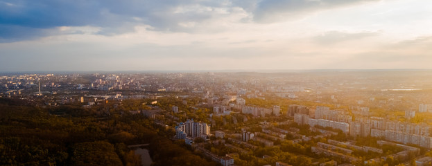 Shot of a city located at the edge of a forest, and a sky, during sunrise.