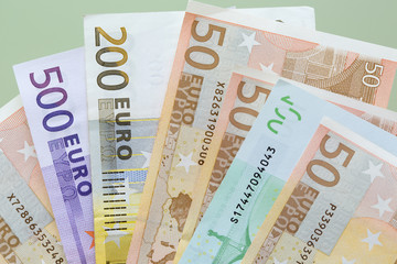 Euro banknotes close-up of different denominations lie on green background.