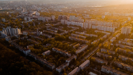 Shot of a city located at the edge of a forest, and a blue sky, during sunrise.