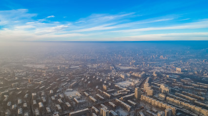 Naklejka na ściany i meble Aerial view of a city and a small forest, during a snowy winter.