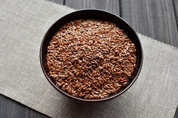 flax seeds in bowl on linen fabric background