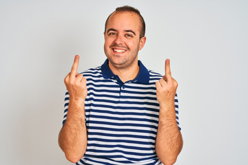 Young man wearing casual striped polo standing over isolated white background Showing middle finger...
