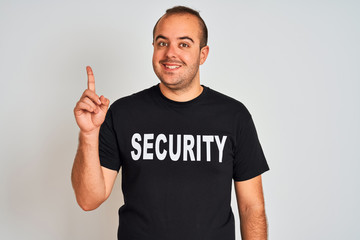Young safeguard man wearing security uniform standing over isolated white background surprised with an idea or question pointing finger with happy face, number one