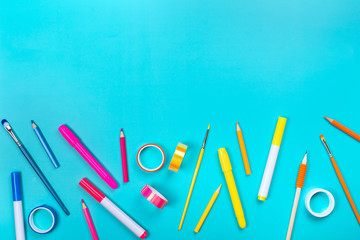 School items as a frame on blue background. Trendy colors, flat lay style. Back to school concept.