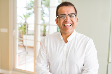 Middle age man wearing glasses smiling to the camera at home