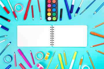 School items as a frame on blue background. Trendy colors, flat lay style. Back to school concept.