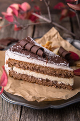 Sliced chocolate biscuit cake with coconut cream. A portion of dessert on wooden boards.