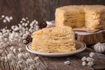 Round multi-layered cake Napoleon with custard, on a  wooden table background. Selective focus