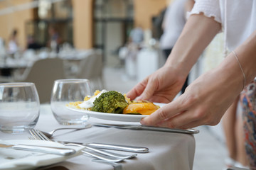 Woman putting a plate full of healthy food on the table, ready to eat concept