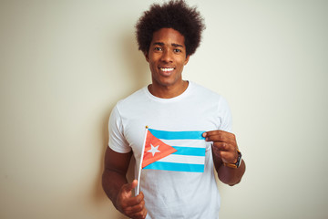 Young african american man holding Cuba Cuban flag standing over isolated white background with a...