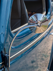 Exterior of a dark blue car with mirror and decorative trim on door.