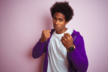 Young african american man wearing purple sweatshirt standing over isolated pink background Ready...