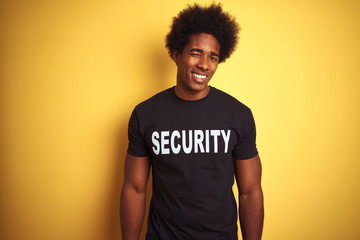 American safeguard man with afro hair wearing security uniform over isolated yellow background...